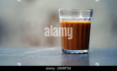 Tè di masala indiano o chai in vetro tradizionale, sfondo di legno. caffè, retrò, ristorante, hotel. Il chai di taglio di prima mattina Foto Stock