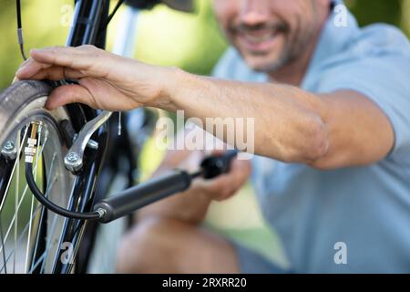 ciclista in nero abbigliamento sportivo tenendo la pompa in entrambe le mani Foto Stock