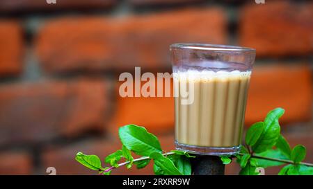 Tè di masala indiano o chai in vetro tradizionale, sfondo di legno. caffè, retrò, ristorante, hotel. Il chai di taglio di prima mattina Foto Stock