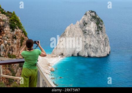 donna o donna anziana o di mezza età che fotografa formazioni rocciose sulla costa di keri a zante in grecia. Foto Stock