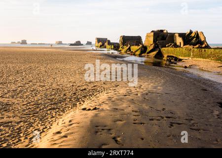 Resti di cassoni Phoenix sulla sabbia, utilizzati per costruire il porto di Mulberry a Gold Beach ad Arromanches, in Francia, dopo gli sbarchi in Normandia nella seconda guerra mondiale. Foto Stock