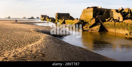 Resti di cassoni Phoenix sulla sabbia, utilizzati per costruire il porto di Mulberry a Gold Beach ad Arromanches, in Francia, dopo gli sbarchi in Normandia nella seconda guerra mondiale. Foto Stock