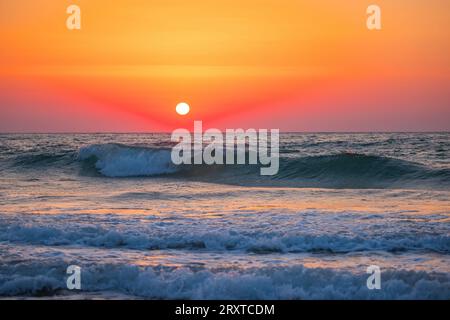 Alba sull'orizzonte del mare e onde che si infrangono sulla sabbia della spiaggia Foto Stock