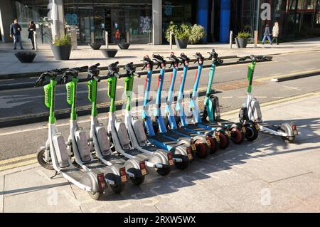 Una linea di scooter elettrici da Lime, Dott e Tier a noleggio/noleggio parcheggiati su un marciapiede di Londra. scooter elettrico, e scooter, e scooter, uk Foto Stock