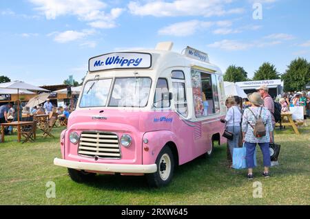 La gente fa la fila ad un furgone rosa vintage Mr Whippy gelato in estate al RHS Hampton Court Palace Garden Festival, precedentemente Hampton Court Flower Show, Regno Unito Foto Stock