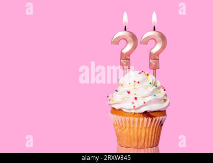 Torta di compleanno con candela due punto interrogativo - su sfondo rosa. Foto Stock