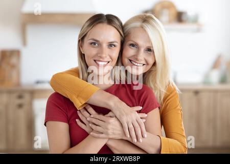 Ama la madre anziana che abbraccia la sua giovane figlia adulta Foto Stock