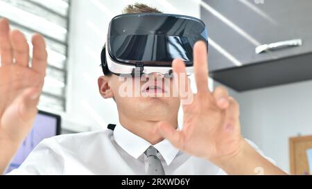 Giovane Trader Man che lavora in ufficio con occhiali VR. Tecnologia VR Virtual Reality Foto Stock