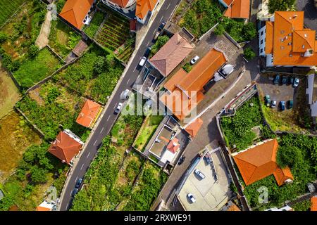 Vista panoramica a volo d'uccello del centro storico della piccola città di Porto Moniz con la sua chiesa, le tipiche case portoghesi e i lussureggianti giardini circostanti Foto Stock