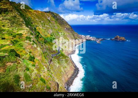 Splendida vista panoramica da cartolina sui ripidi pendii della costa nord di Madeira con Porto Moniz, Portogallo, sullo sfondo Foto Stock