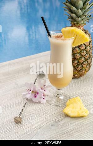 Cocktail estivo, Piña colada. Su un tavolo bianco all'aperto, decorato con ananas e fiori. Foto Stock