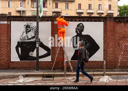 Milano, Italia - 21 aprile 2023: Un lavoratore sta mettendo sui muri dei manifesti della collezione Moncler del 2023 Foto Stock