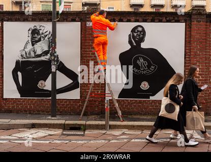 Milano, Italia - 21 aprile 2023: Un lavoratore sta mettendo sui muri dei manifesti della collezione Moncler del 2023 Foto Stock