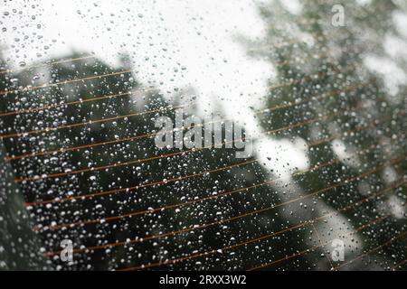 Vetro per auto bagnato. Gocce di pioggia sul vetro dell'auto. Superficie bagnata. Elemento riscaldante in vetro di trasporto. Foto Stock