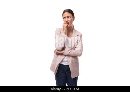 giovane donna bruna, intelligente e ben curata, vestita con una giacca beige pensata su uno sfondo bianco con spazio per le copie Foto Stock