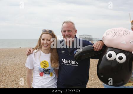 Brighton, Regno Unito. 27/settembre/2023 Norman Cook e Shaun the Sheep Sculptures a Brighton Norman Cook, alias Fatboy Slim, cammina per mezza maratona attraverso Brighton visitando una serie di sculture Shaun the Sheep appositamente decorate. La passeggiata è sponsorizzata e le statue sono state create per raccogliere fondi per il Martlets Hospice in città. Presso il Palace Pier Norman Cook incontra l'artista Lauren Nickless e lo Shaun che ha decorato chiamato "Sheep DIP". Nella foto: Lauren Nickless, Norman Cook e Shaun. Credito: Roland Ravenhill/Alamy. Foto Stock