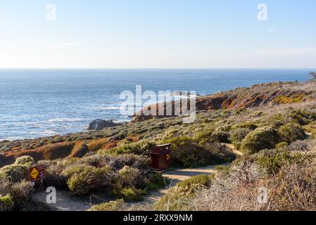 Cestino di riciclaggio lungo un sentiero costiero deserto sulla costa della California in una soleggiata giornata autunnale Foto Stock