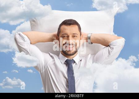 Ritratto di un uomo d'affari che riposa su un cuscino in camicia e cravatta nel cielo Foto Stock