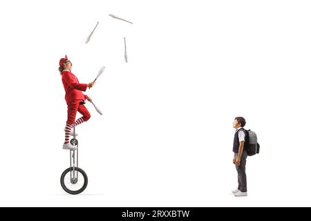 Scolaro che guarda un acrobato mentre cavalca un uniciclo di giraffa e giocola isolato su sfondo bianco Foto Stock