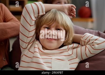 Ritratto in primo piano di un simpatico ragazzo biondo che sorride davanti alla fotocamera mentre si gioca all'asilo o all'asilo Foto Stock