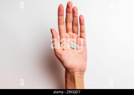 La mano di una donna che tiene una pillola, isolata sullo sfondo bianco Foto Stock