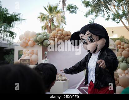 Clown o personaggio che gioca con i bambini. festa di compleanno all'aperto per bambini. Bambini che giocano con il clown. bambini che giocano con la persona che indossa micky mouse Foto Stock