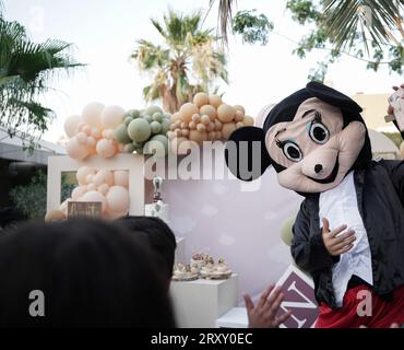 Clown o personaggio che gioca con i bambini. festa di compleanno all'aperto per bambini. Bambini che giocano con il clown. bambini che giocano con la persona che indossa micky mouse Foto Stock