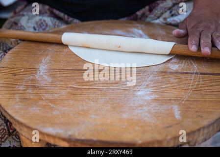 Mattonella in donna che arrotola l'impasto a mano su un tradizionale mini tavolo, preparare il Gozleme è uno spuntino turco tradizionale. Foto di alta qualità Foto Stock