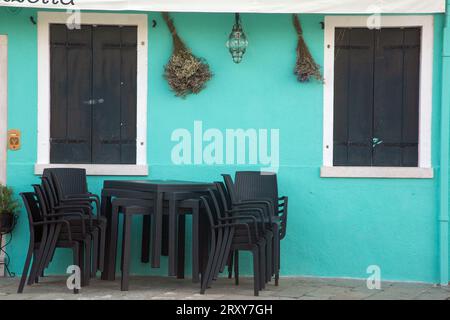 Burano, Venezia, Italia, settembre 2023, tavoli e sedie di plastica impilati all'esterno di un ristorante sull'isola Foto Stock