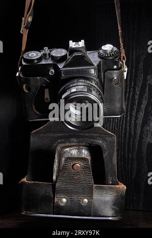 Una vecchia fotocamera reflex con telemetro a film in una custodia usurata Foto Stock