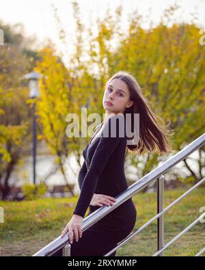 Bella ragazza che posa sui gradini in un parco autunnale Foto Stock