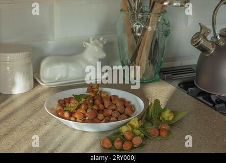 Ciotola bianca di nocciole appena raccolte su una superficie della cucina Foto Stock