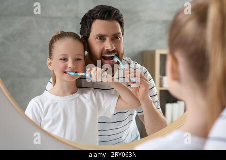 Padre e sua figlia lavano i denti insieme vicino allo specchio in bagno Foto Stock