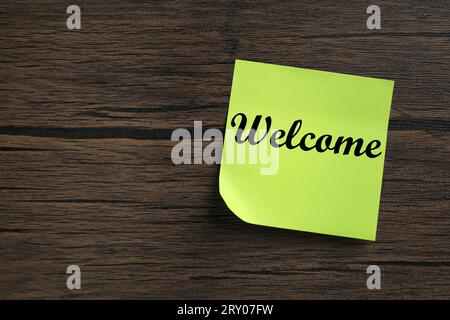 Nota adesiva con la parola Welcome on Wooden table, vista dall'alto. Spazio per il testo Foto Stock