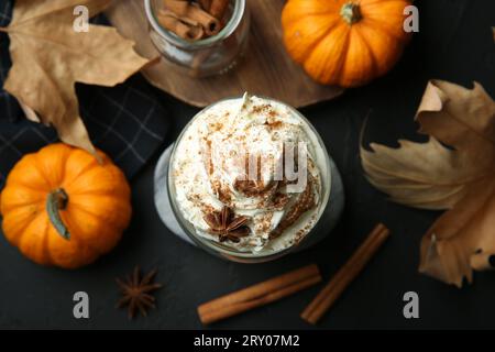 Composizione piatta con bicchiere di latte di zucca speziata su tavolo nero Foto Stock