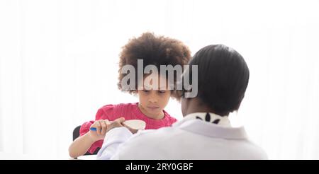 Dentista afroamericano che spiega ai bambini afro di razza mista come lavarsi i denti. Il concetto medico e sanitario per i bambini. Foto Stock