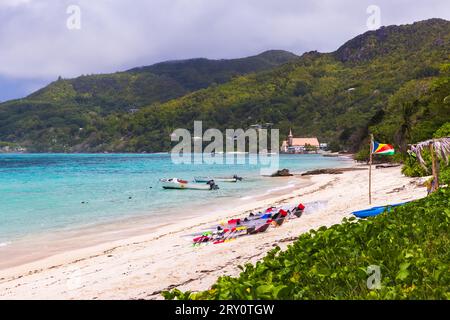 Paesaggio estivo sulla spiaggia di anse Royale con kayak in plastica trasparente a noleggio e bandiera delle Seychelles in una giornata di sole Foto Stock