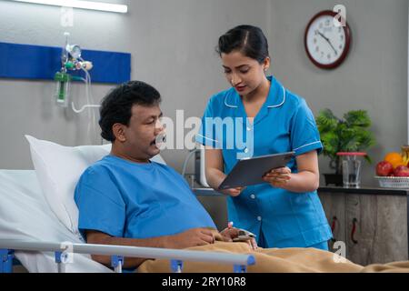 Infermiera indiana che spiega circa rapporto medico o chiedendo condizione di un paziente ricoverato in ospedale da appunti - concetto di valutazione del trattamento Foto Stock