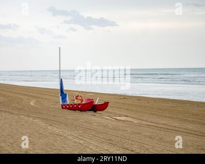 Lettini e ombrelloni bagnati sulla spiaggia di mare durante le giornate piovose. Ombrellone arrotolato sulla spiaggia contro nuvoloso scuro Foto Stock