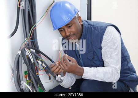 elettricista che controlla il livello di tensione nei cavi della presa a muro Foto Stock