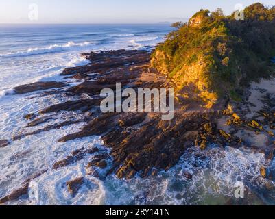 Vista aerea delle onde che si infrangono contro un promontorio roccioso a Nambucca Heads nel nuovo Galles del Sud, Australia. Foto Stock