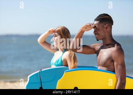 un paio di body boarder che guardano il mare Foto Stock