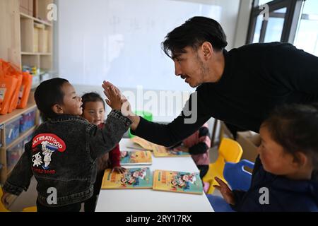 (230928) -- YUSHU, 28 settembre 2023 (Xinhua) -- Tsering Dradul (2nd R), il vice preside di un asilo, interagisce con un ragazzo all'asilo nella contea di Qumarleb della prefettura autonoma tibetana di Yushu, provincia del Qinghai della Cina nord-occidentale, 14 settembre 2023. La contea di Qumarleb si trova nella regione sorgente del fiume giallo, con un'altitudine media di oltre 4.500 metri. Qui i bambini conducono una vita nomade con le loro famiglie su ampie praterie lontano dai capoluogo di contea e dalle città. Attraverso anni di sforzi da parte del governo locale, l'istruzione prescolare gratuita è stata estesa alle aree di pascolo. J Foto Stock