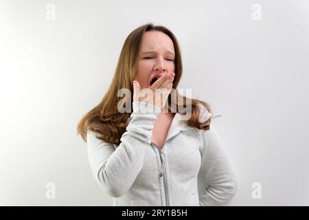 Donna stanca che sbadigna coprendo la bocca aperta con la mano bisogno di riposo. La giovane lavoratrice addormentata non può svegliarsi avendo insonnia. Reazione a catena. Foto di alta qualità Foto Stock