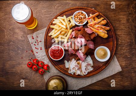 Ampia scelta di spuntini per birra o alcol e include carne di maiale affumicata, patatine fritte, pane fritto, bastoncini di granchio e noci servite con salse su legno Foto Stock