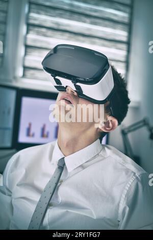 Uomo d'affari con occhiali VR che lavora in ufficio. Concetto interattivo di business e tecnologia. Primo piano Foto Stock