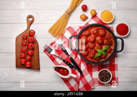 Polpette in salsa di pomodoro con spezie in padella e pomodori ciliegini su un tagliere e un tagliere di legno bianco. Vista dall'alto. Foto Stock