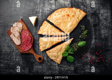 Pizza tradizionale italiana con ingredienti su pietra e fondo di legno scuro graffiato. Vista dall'alto. Foto Stock