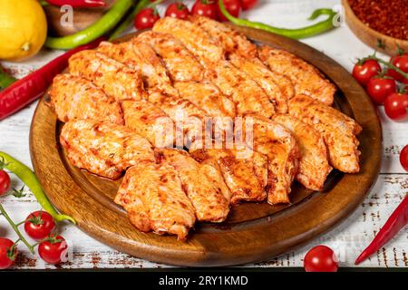 Ali di pollo con salsa su fondo di legno. Ali di pollo crude con erbe e spezie Foto Stock