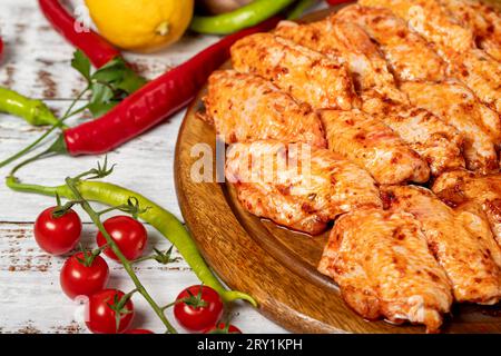 Ali di pollo con salsa su fondo di legno. Ali di pollo crude con erbe e spezie Foto Stock